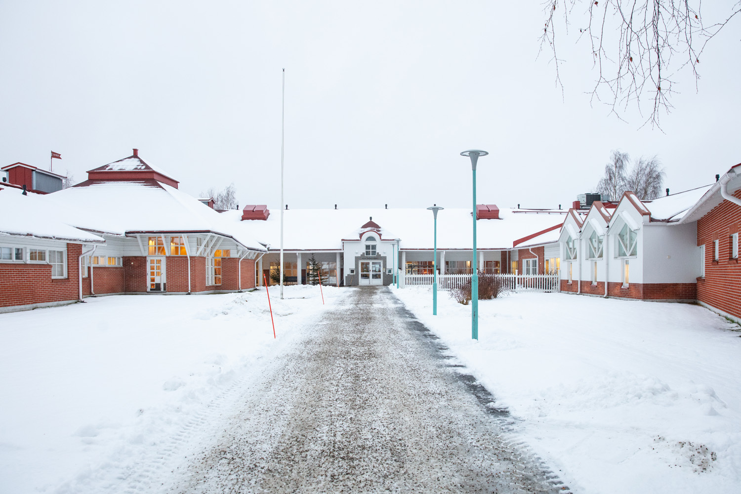 rakennuksen edusta talviaikaan. Rakennuksen pääsisäänkäynnille johtaa tie.