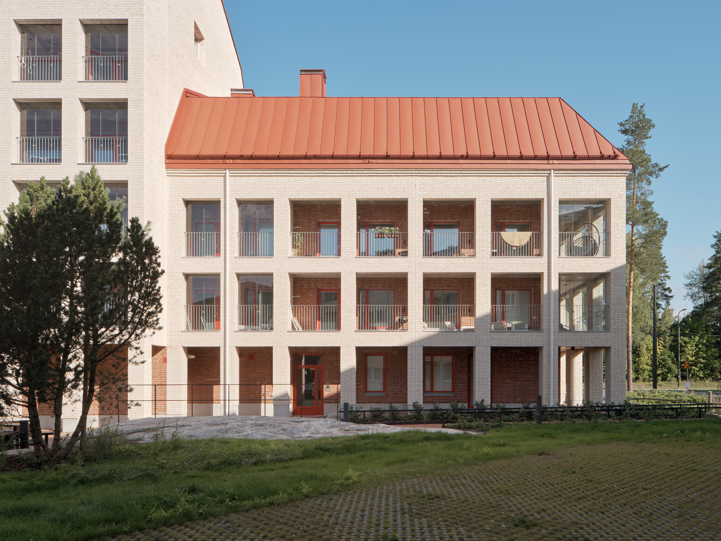 Vaalea punakattoinen tiilikerrostalo.