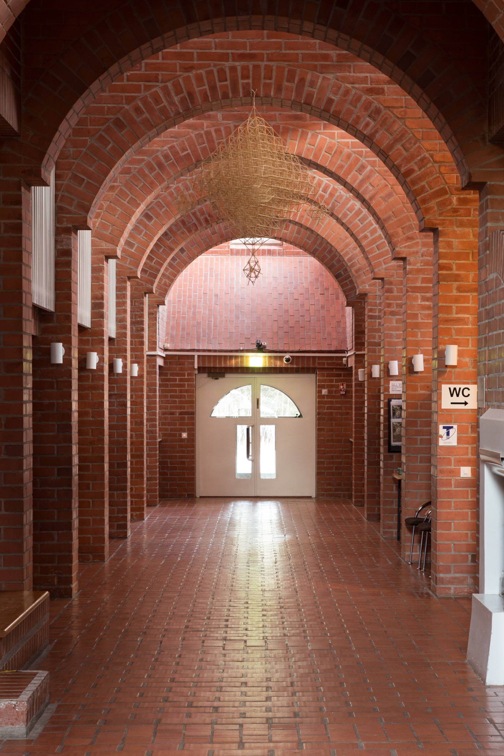 tiilinen käytävä, jonka päässä ikkunallinen ovi