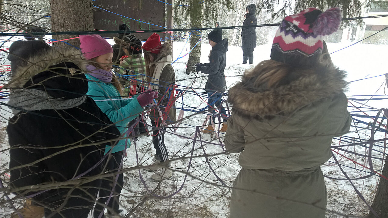 Lapset rakentavat naruista sokkeloa lumisessa metsässä