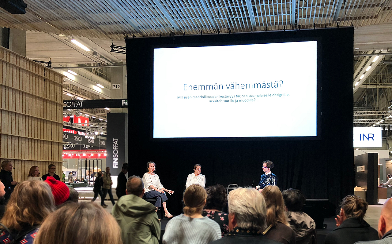 Paneelikeskustelu suuressa salissa, jossa seinälle heijastettu diaesitys