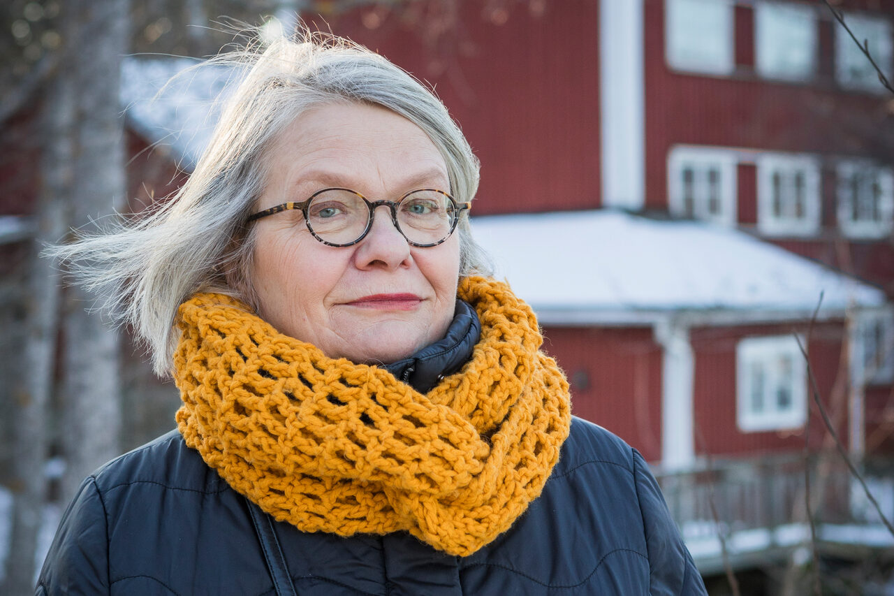 Silmälasipäinen nainen keltaisessa kaulahuivissa lähikuvassa