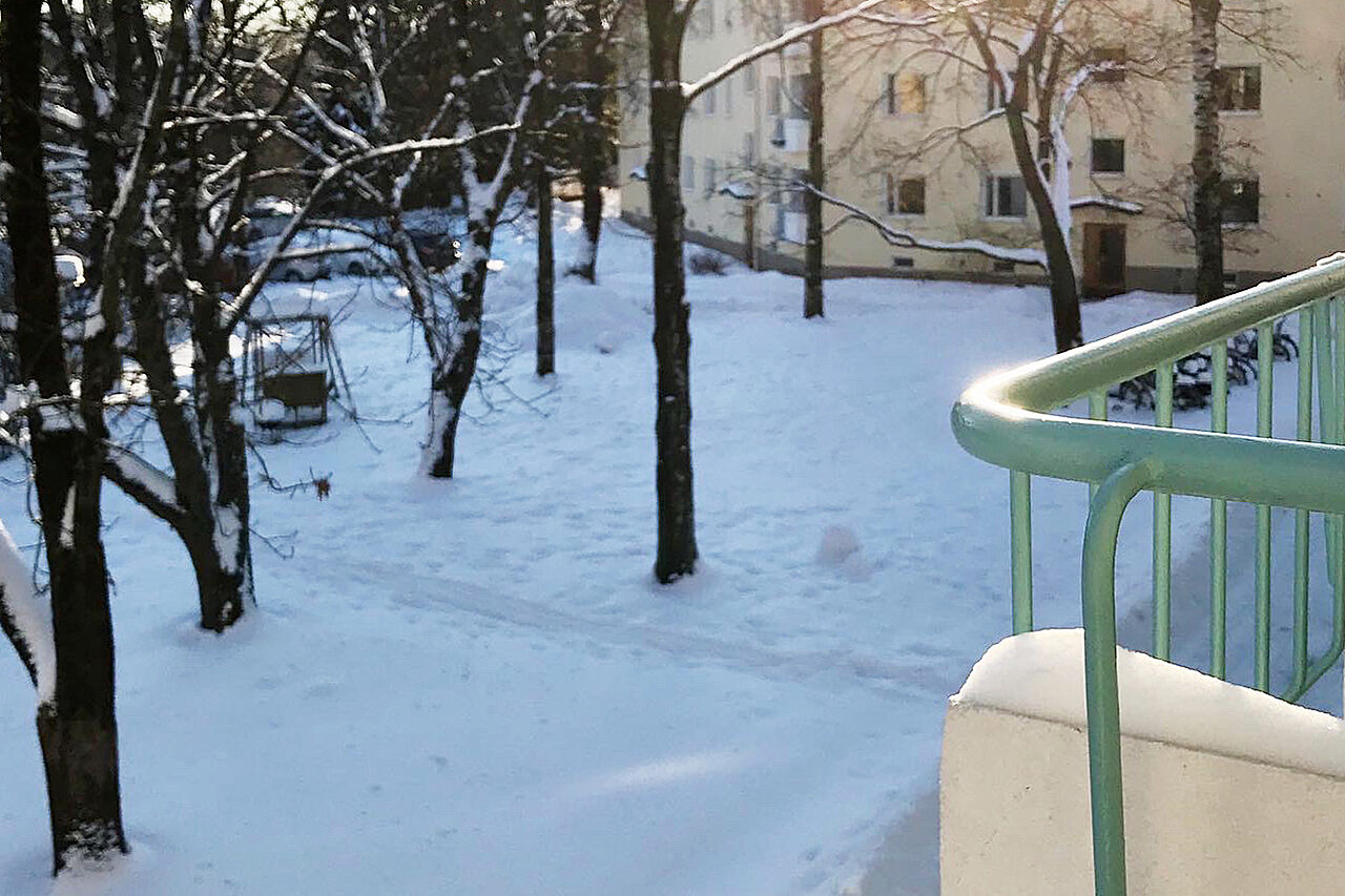 Parvekkeen kaide, näkymä lumiselle pihalle.