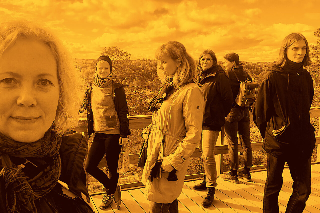 Kuva archinfolaisista nuuksiossa. Kuva on mustaoranssi. Archinfolaiset seisovat hajallaan näköalapaikalla.