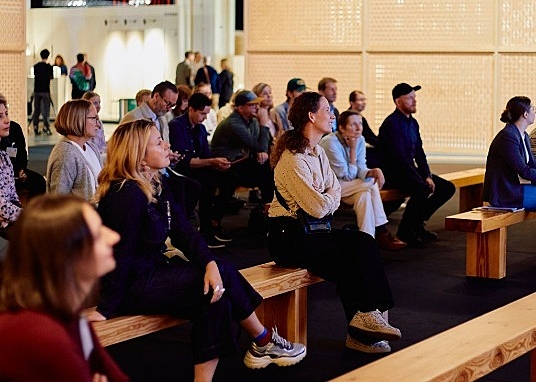 Ihmisiä istumassa tuoleilla katsoen esitystä.