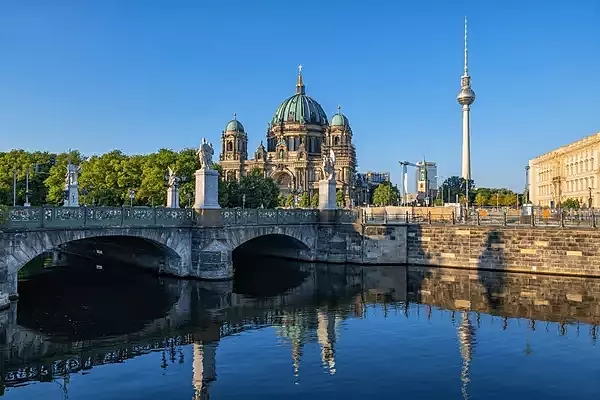 A view of a city, including a cathedral, TV tower and canal crossed by a bridge.