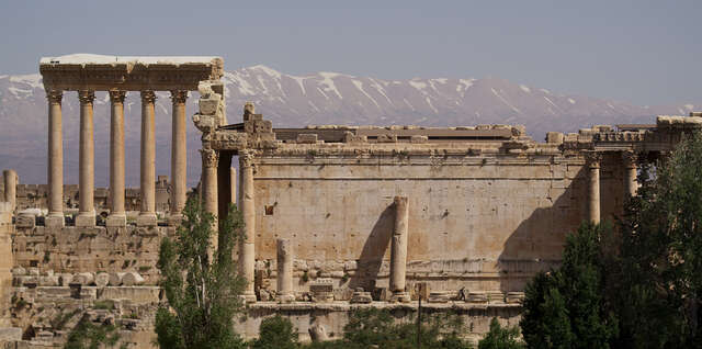 An immense ancient Roman ruin, mountains in the background