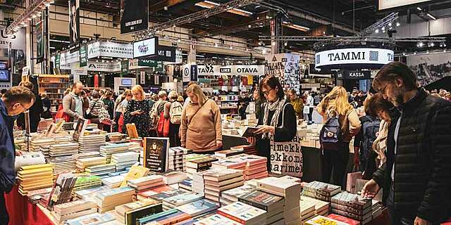 Paljon ihmisiä katselemassa kirjoja pöydillä