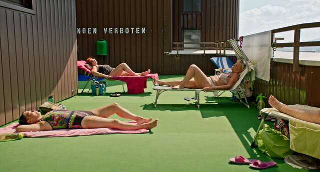 Naisia ottamassa aurinkoa vihreällä terassilla.