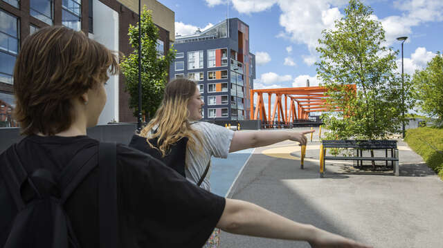 Kaksi nuorta kävelevät peräkkäin levittäen käsiään.