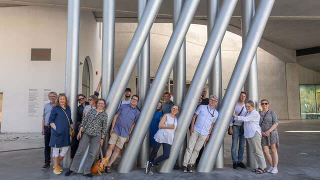 Joukko ihmisiä nojailemassa pylväisiin.