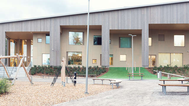 Puurakenteinen päiväkotirakennus, pihalla leikkitelineitä.