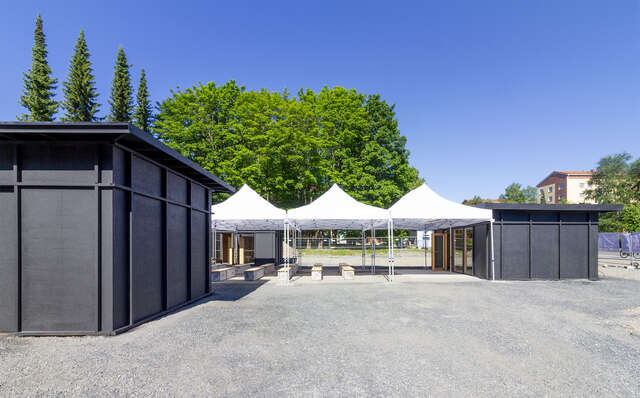 Vasemmalla etualalla on musta paviljonki. Oikealla taaempana on toinen musta paviljonki ja sen vieressä valkoisia telttamaisia paviljonkeja.