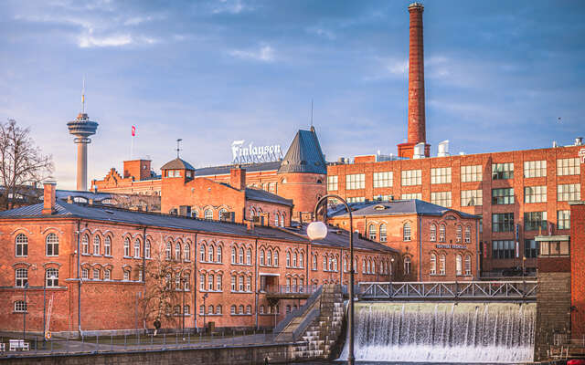 Punatiilinen teollisuusrakennuskompleksi vesiputouksen äärellä.