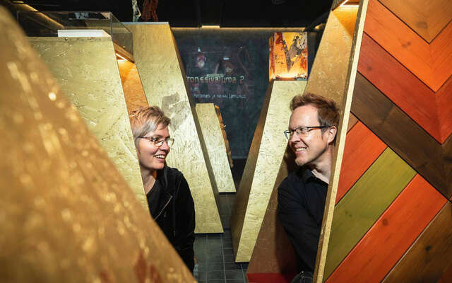 Nainen ja mies kurkkivat levyjen välistä.