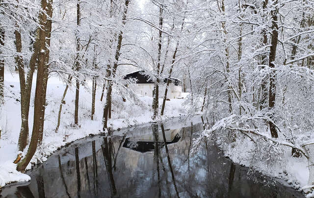 Talvinen kuva jokilaaksosta, kauempana rakennus