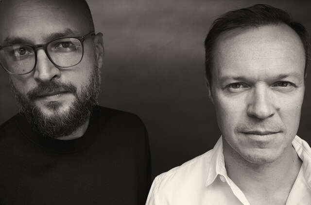 Kaksi miestä katsovat kameraan