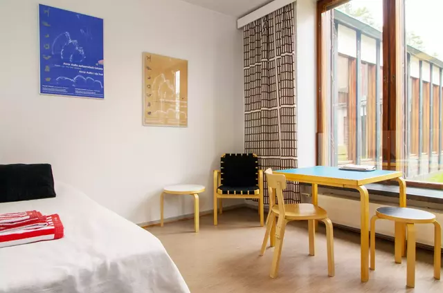 Room with a bed and a table and two chairs next to the window