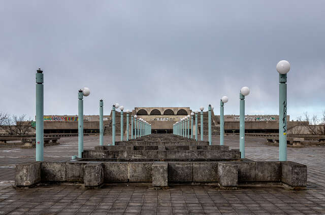 Siniset valopylväät muodostavat käytävän vanhalle betonirakennukselle.
