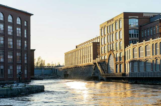 Photo of two old factory buildings near a river.