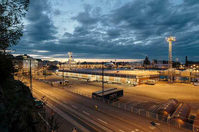 Leveä tie ja matala rakennus sataman tuntumassa iltavalaistuksessa.