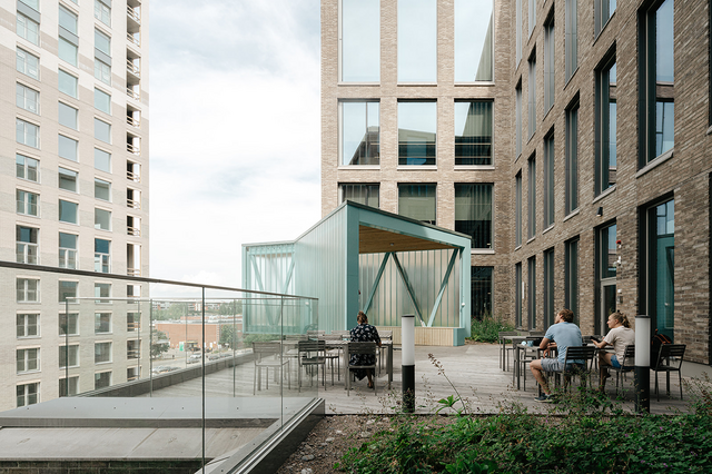 Kuva kerrostalojen välissä olevasta pihasta, jossa istuu ihmisiä