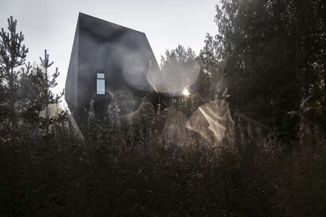 A foggy photo of a strangely-formed, object-like house in the midst of a forest