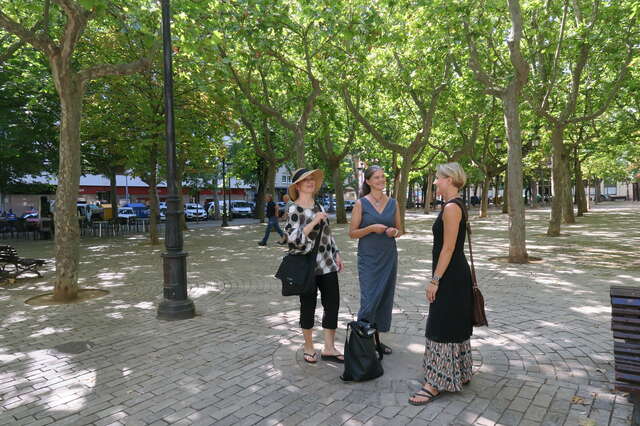 Three women are standing in the park.