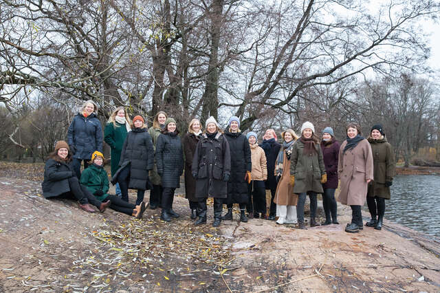 A group of people on a rocky shoreline slope in cool weather.