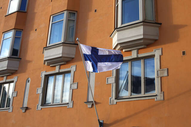 Lippu liehuu oranssin rakennuksen edustalla.