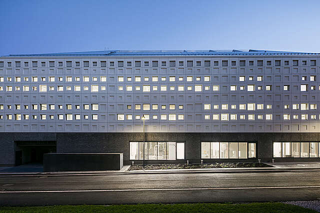 Iltakuvassa valkoinen julkisivu, jossa erikokoisia neliön muotoisia ikkunoita