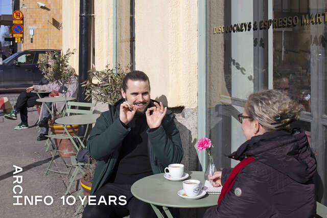 A man and a woman having coffee on a street terrace.