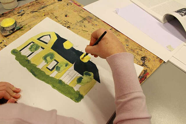 Lapsi maalaa kuvaa talosta.