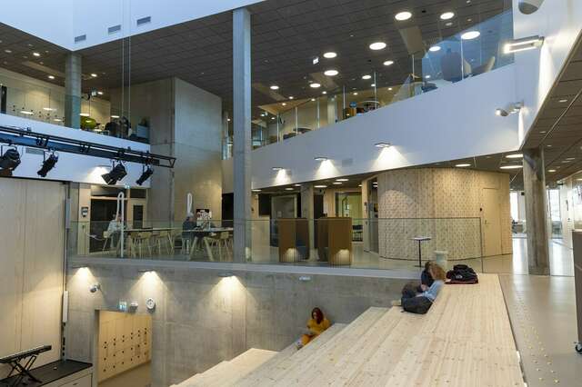 Lukion betonipintainen auditorio, muutama opiskelija työskentelee tietokoneilla