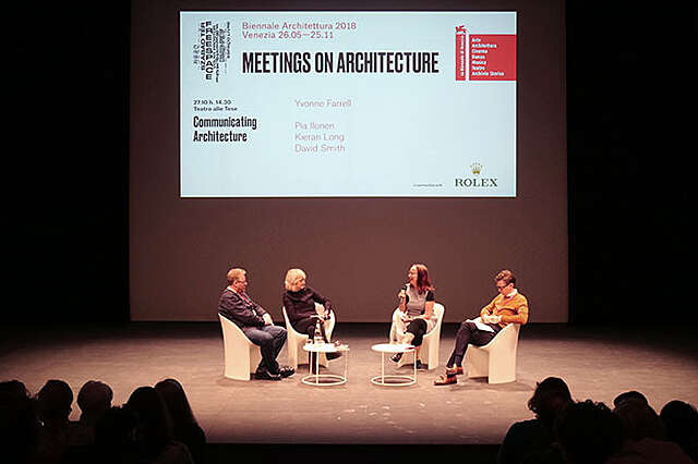 Neljä ihmistä lavalla, taustalla diaesitys aiheesta