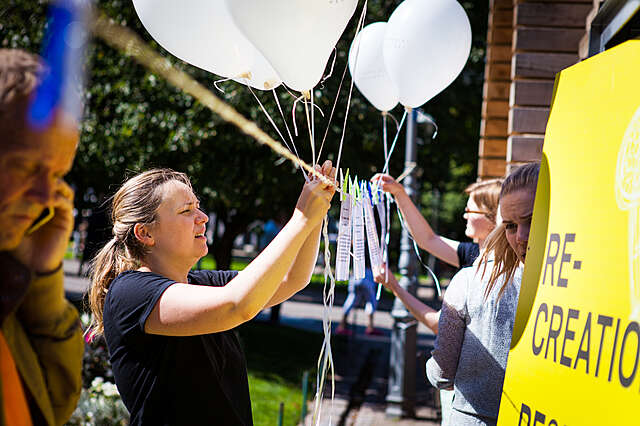 Nainen kiinnittää ilmapalloja pyykkinarulle kesätapahtumassa.
