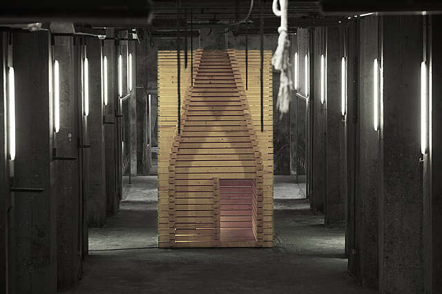 A work of art made of planks in a dark industrial room.