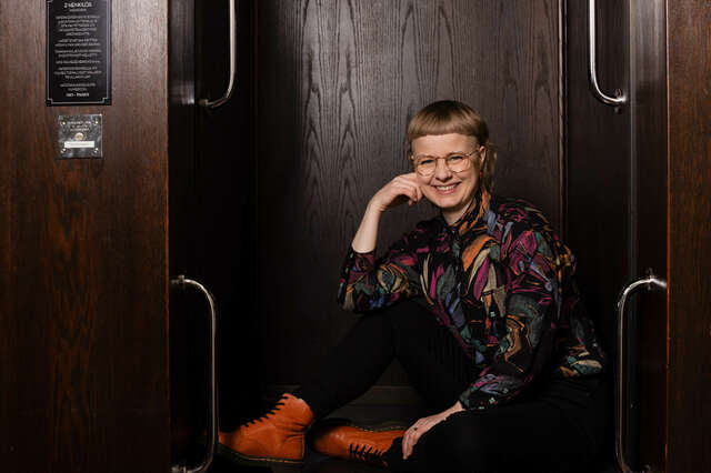 Kuvassa lyhythiuksinen nainen, joka katsoo kameraan. Hänellä on kirjava paita.