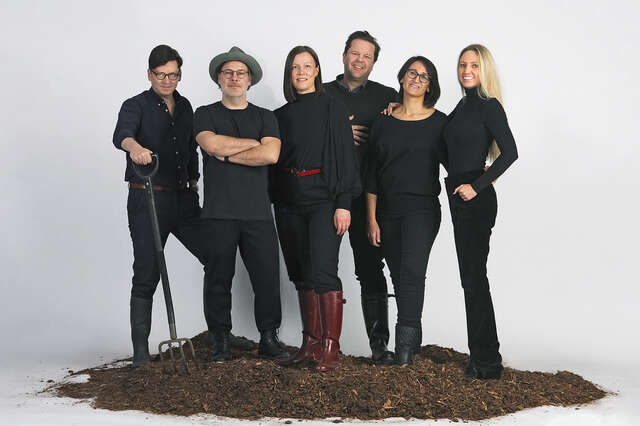 A group of people dressed in dark clothes, standing side by side on a litter tray.