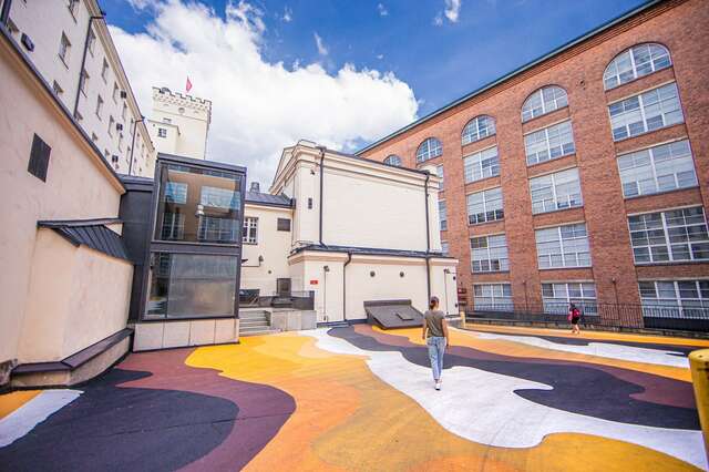 Etualalla värikkäitä maalauksia asvaltilla. Taka-alalla rakennuksia.