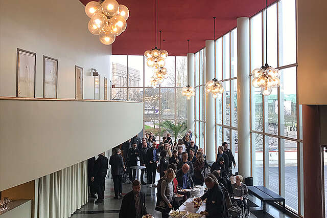 Bio Rexin aulan avarassa tilassa ihmisiä. Suuret ikkunat ja punainen katto luovat tunnelmaa.