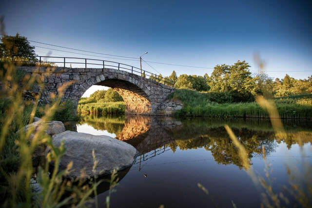 Tyyni jokimaisema, kivinen kaarisilta.