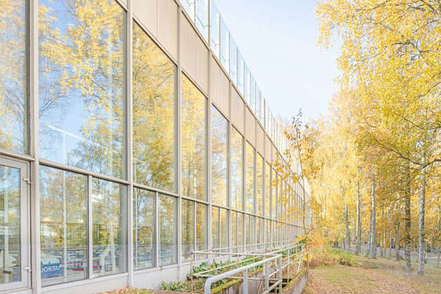 Riihimäen uimahallin seinän suuriin ikkunoihin heijastuu viereisen urheilupuiston puiden ruska.