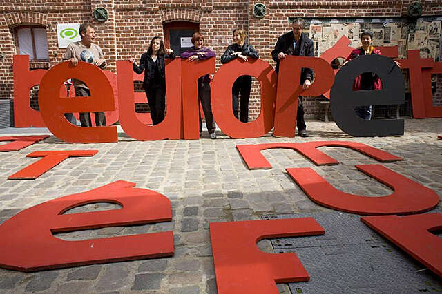 Isoja punaisia kirjaimia torilla. Ihmiset pitävät joitain kirjaimista pystyssä.