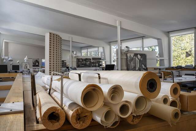 Useita vanhoja paperirullia etualalla, taustalla toimistotila