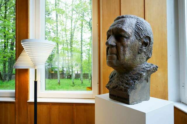 Pronssinen rintakuva miehestä, vieressä lattiavalaisin