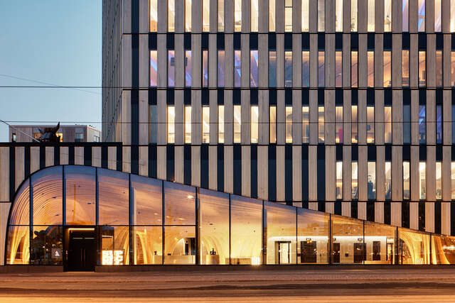 Lähikuva suuren talon kaarevasta sisääntuloseinän aukosta iltavalaistuksessa