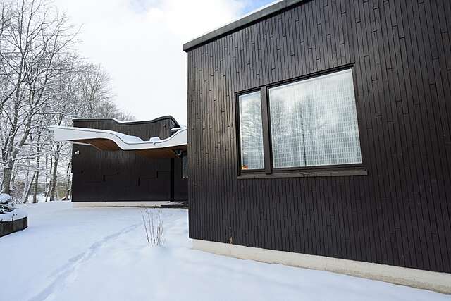 tumma puurakenteinen rakennus talvisessa maisemassa