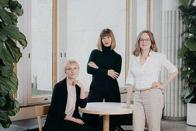 VAPAA collectiven arkkitehtehtien ryhmäkuva. Karkulahti, Wiikinkoski ja Nyholm ovat kerääntyneet pöydän ääreen.