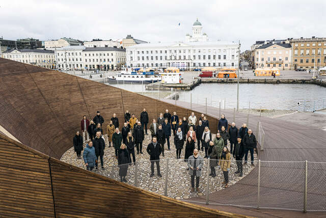 A group of people next to a wooden pavilion building.